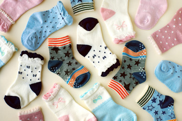 Baby socks on white background. Many socks for baby are scattered on a white background. View from above. Clothes for children from jersey. - obrazy, fototapety, plakaty