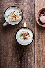 Healthy cauliflower cream soup in rural mugs, top view
