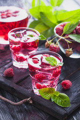 Red raspberries cocktail with ice and fresh mint on a old wooden table