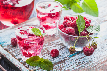 Red raspberries cocktail with ice and fresh mint on a old wooden table