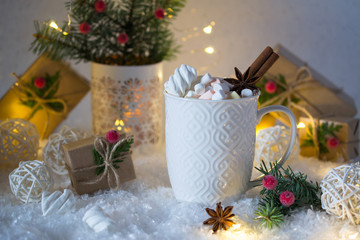 Hot chocolate in a white cup with marshmallows and Christmas gifts on the bright light background. Christmas drink.