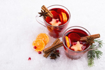 Traditional hot drink at Christmas time. Christmas mulled red wine with spices and fruits. On white snow background