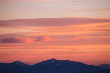 A view of some mountains top, beneath a beautiful, warm colored sky at sunset