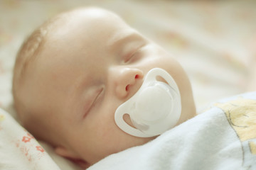 Newborn baby boy is sleeping with white dummy