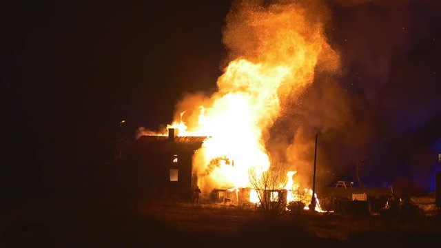 Explosion in burning house causing a huge burst of fire to shot out from the house