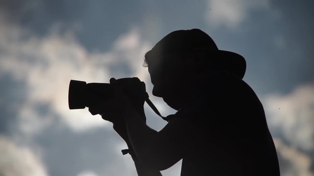 Silhouette of a young photographer with snapback cap