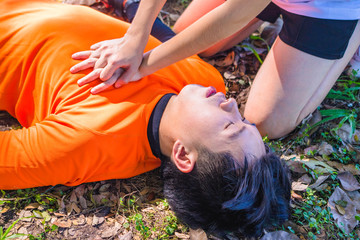 First Aid Emergency CPR. After Bicycle Race A Cyclist man has Heart Attack or Shock. A woman  give CPR for first aid Cyclist man. Emergency , safe life , Photo concept Heart Attack and CPR. 