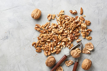 Walnut kernels on gray background with nutcracker.