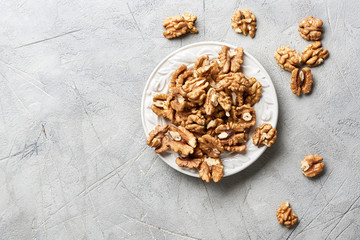 Obraz na płótnie Canvas Walnut kernels on white plate over gray background.