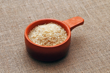 Preparation of rice in a clay pot against the background of a sackcloth