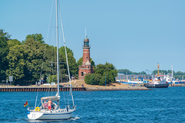 Segelyacht aus dem Kanal kommend passiert den Leuchtturm Holtenau