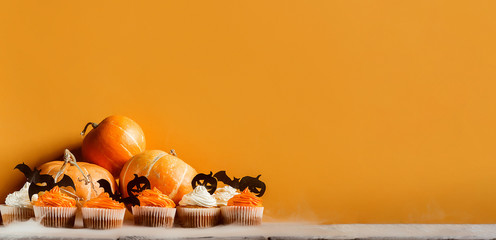 cupcakes and pumpkins to celebrate halloween on a background with space for text