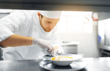 food cooking, profession and people concept - happy male chef cook serving plate of soup at restaurant kitchen
