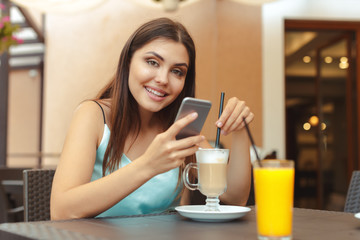 Portrait of beautiful girl using her mobile phone in cafe