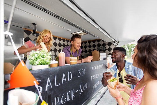 street sale, payment and people concept - happy customers buying burger at food truck