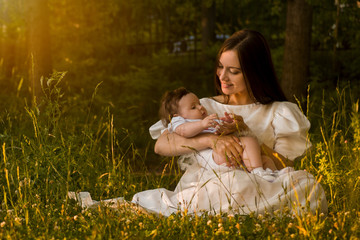 beautiful young mother with a little daughter in the forest at a photo session near the pond