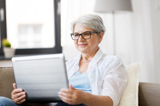 technology, old age and people concept - happy senior woman in glasses with laptop computer at home