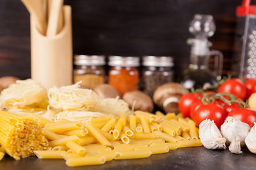 Healthy and delicous meal - raw uncooked pasta next to vegetables on rustic vintage wooden...