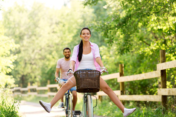 cycling, leisure and lifestyle concept - happy young couple with bicycles at summer park