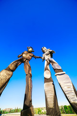 People in robot costumes pose against a blue sky.