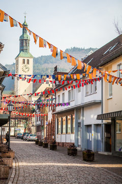 Perspective of a traditional alleyway in small town of Southern Germany with old architecture with decorations for national celebration