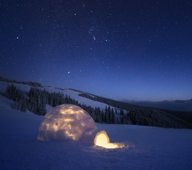 Winter night landscape with a snow igloo and a starry sky