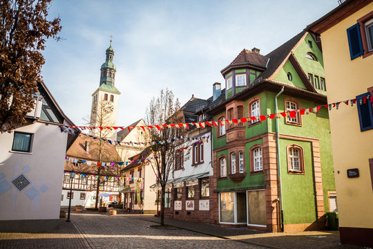 Perspective of a traditional alleyway in small town of Southern Germany with old architecture with decorations for national celebration