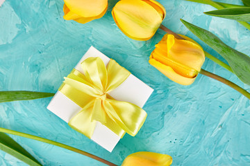 Gift box with yellow ribbon near tulip