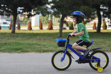 Five years old boy rides a bicycle in the city. Child riding bicycle outdoor on sunny day