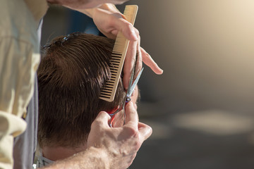 Hands of a hairdresser close-up of scissors and a comb. The barber is cutting a man and doing a haircut. Horizontal photo with text place.
