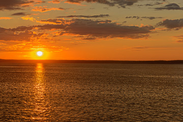bright sun descends the horizon above the river