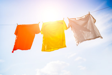 Photo of three T-shirts hanging on rope against blue sky background