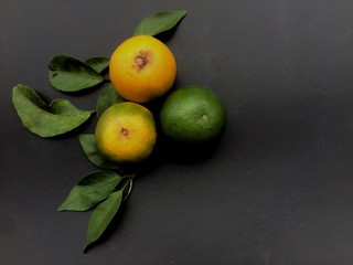 Isolate orange fruit and leaf on black background.