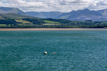 Tidal water of Menai Strait and Snowdonia mountains in the background in summer