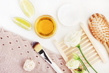 Organic ingredients for homemade spa and hair care with essential oil, lime, aroma flowers. Wooden beauty treatment accessories top view with bathroom towels. 