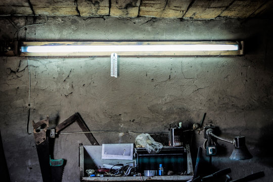 Old work tools, shelf on a wall over an old vintage workbench  in a home garage