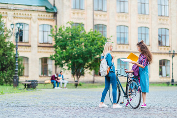 students with bicycle and notebooks standing on street near university