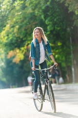 smiling student with backpack riding bicycle on street