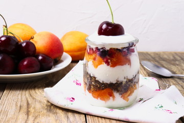 Glass dessert made of yogurt, granola, apricots and cherries