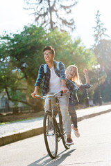 happy multiethnic students riding bicycle together on street