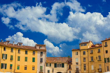 Fototapeta na wymiar Beautiful clouds over the famous Piazza dell'Anfiteatro (Amphitheater Square) in the historic center of Lucca, with houses built over ancient roman arena ruins