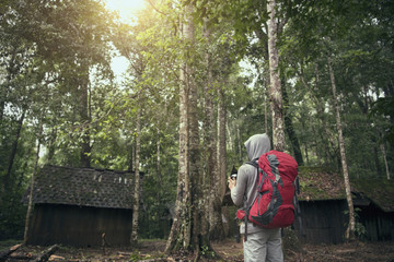 Naklejka na ściany i meble Freedom traveler man standing with backpack and enjoying a beautiful nature forest.