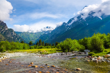 From the river shore opens view on fantastic glacier.  Sky with clouds. Landscape with high...