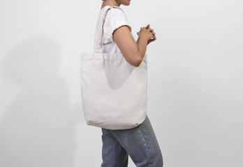 Girl is holding bag canvas fabric for mockup blank template isolated on gray background.