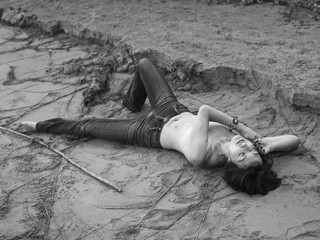 Naked woman in jeans lies on the sand