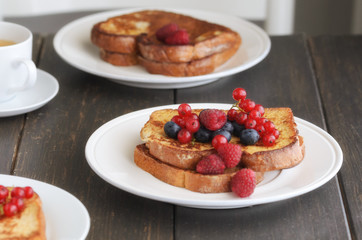 Good breakfast background.  French toasts with berries and icing sugar  cup of coffee on wooden table.