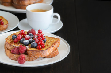 Good breakfast background.  French toasts with berries and icing sugar  cup of coffee on wooden table. Copy space.