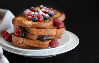Homemade french toast with blueberries; currant berries, raspberries  and icing sugar for perfect  sweet breakfast. Delicious dessert background.Copy space.