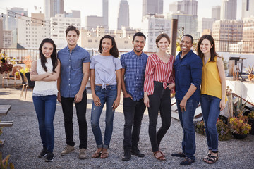 Portrait Of Friends Gathered On Rooftop Terrace For Party With City Skyline In Background