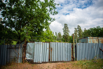 old metal gates topped with barbed wire, locked private property